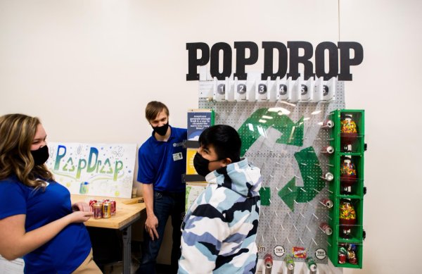pop drop machine in back, three students in front, laughing and engaging