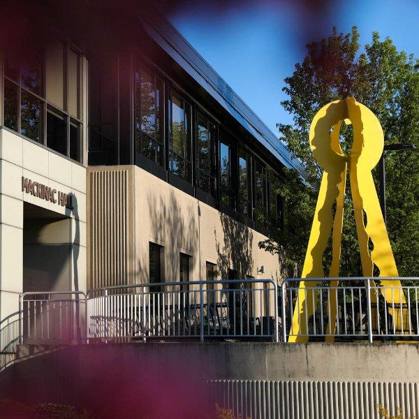 A building with the words Mackinac Hall has a yellow sculpture in front of it.
