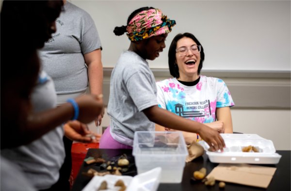 Frederik Meijer Honors College student Sofia Magan, right, laughs with Kentwood's Endeavor Elementary School students while they were looking at rocks and fossils. The students were part of a multicultural leadership team that visited the Allendale Campus May 1. Magan is a sophomore studying biomedical sciences.