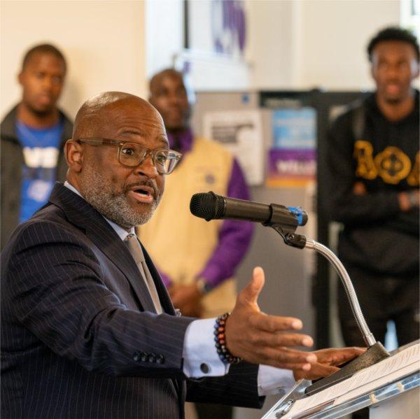 VP Truss at the podium, speaking, three people standing in background