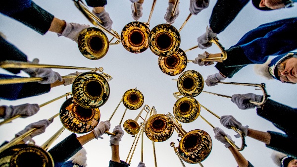 Hands hold instruments above camera with trombone bells facing down toward the camera. 