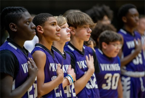 Vanguard Charter Academy players stand with their hands over their hearts during the playing of the national anthem. 