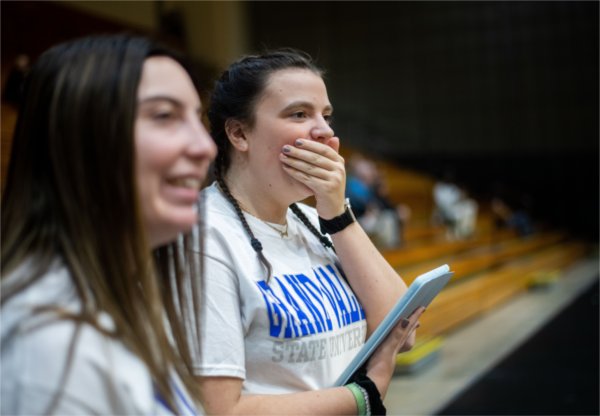 Two Grand Valley students react to a basketball game between two youth teams.