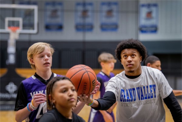 A Grand Valley student grabs a rebound for a youth basketball player.