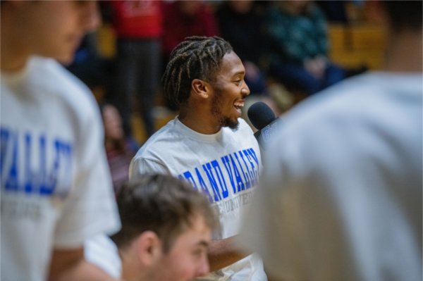 A Grand Valley student laughs laughs with spectators during halftime of a youth basketball game.