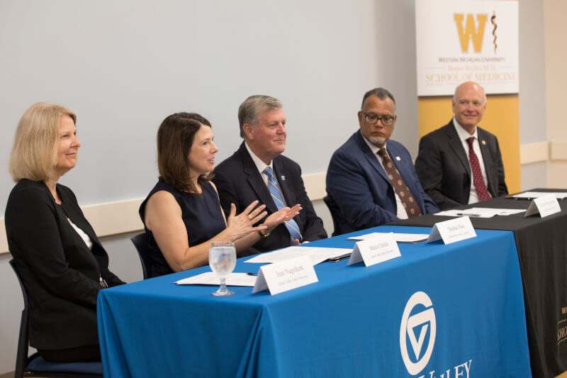 woman talking, four people seated at long table