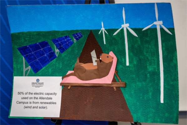 A poster of a groundhog lounging between solar panels and wind turbines. A fact to the left reads &#8220;50% of the electric capacity used on the Allendale Campus is from renewables (wind and solar).&#8221; 