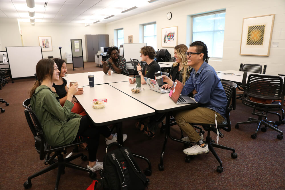 students sitting around a table with refreshments, chatting