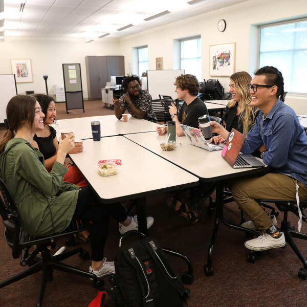 students sitting around a table with refreshments, chatting