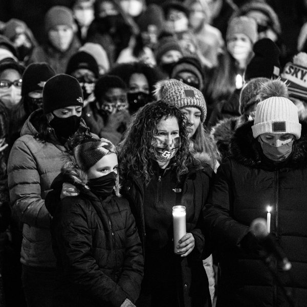 A black and white photo of people holding candles during a vigil held in memory of a GVSU student.