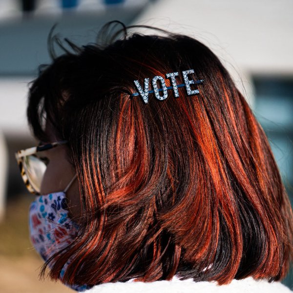 Photo of a person with red hair wearing a barrette that says "vote"