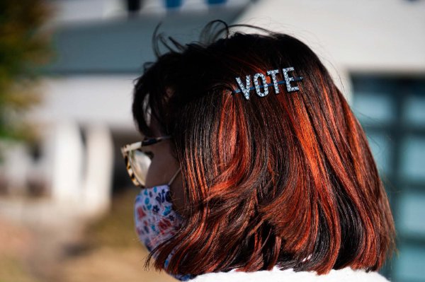 Photo of a person with red hair wearing a barrette that says "vote"