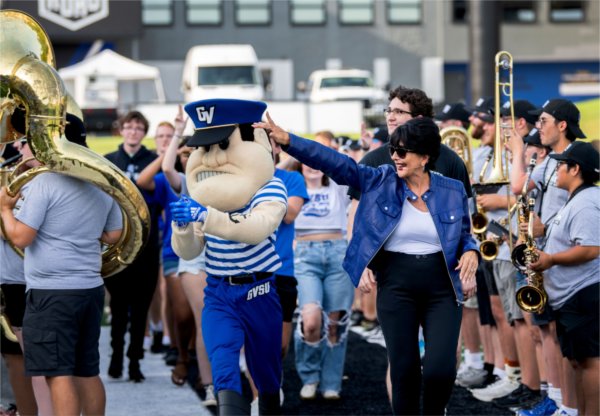 President Philomena V. Mantella waves at students as she walks with Louie the Laker through a tunnel of Laker Marching Band members during Laker Kickoff August 22.  
