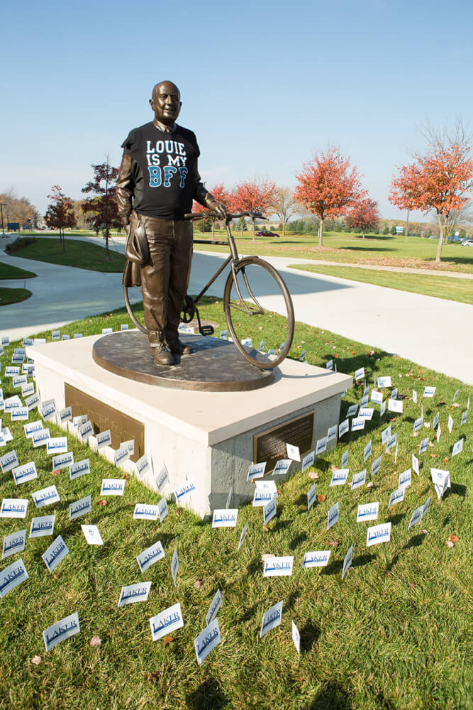 statue of Bill Seidman surrounded by small Grand Valley flags