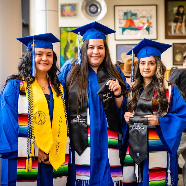 three women in blue graduation gowns and Latino stoles