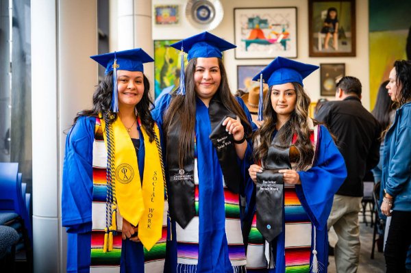 three women in blue graduation gowns and Latino stoles