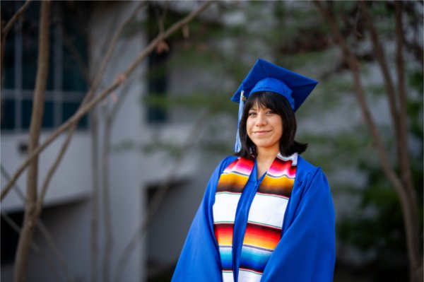 A person in a cap and gown smiles in a posed photo.