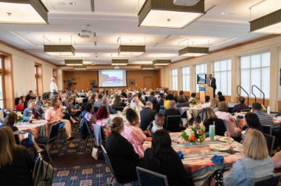 speaker at side behind podium, people seated at round tables