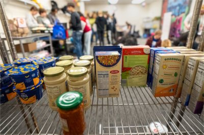 food shelf in Replenish with items, students in background helping to sort items