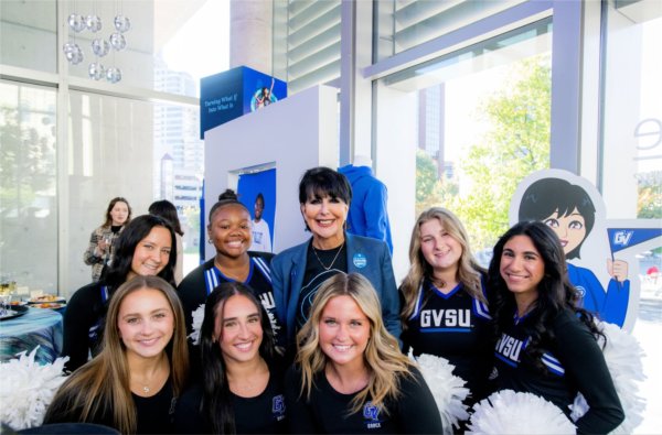 President Mantella stands with members of the GVSU dance and cheer teams inside the Laker Store on Monroe Center
