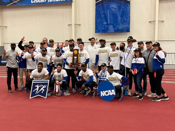 The men's track and field team poses for a photo with the trophy after winning the national championship.