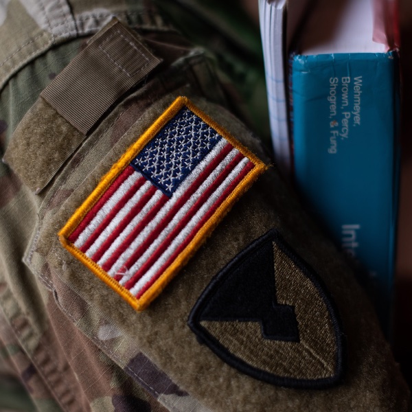 Close up showing American flag patch on uniform of a student veteran holding books.