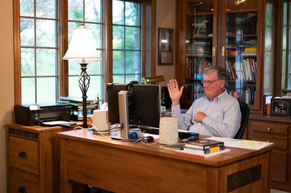 Haas holds up a hand while teaching a class from his home office.