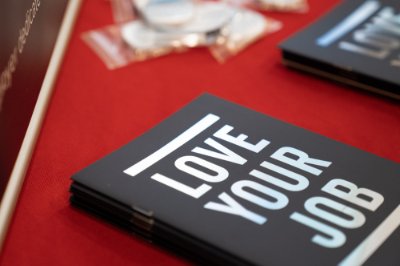 A black notebook that reads "Love Your Job" laying on a table