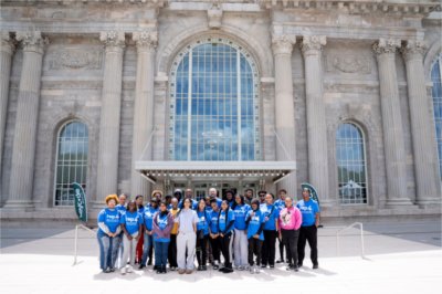 A group of people in blue REP4 shirts stand in front of the ornate entrance of Michigan Central. 