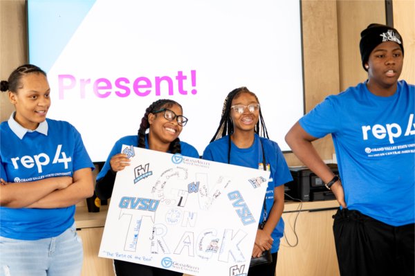 Four people in blue REP4 shirts present a posted that says &#8220;GV on Track&#8221;. 