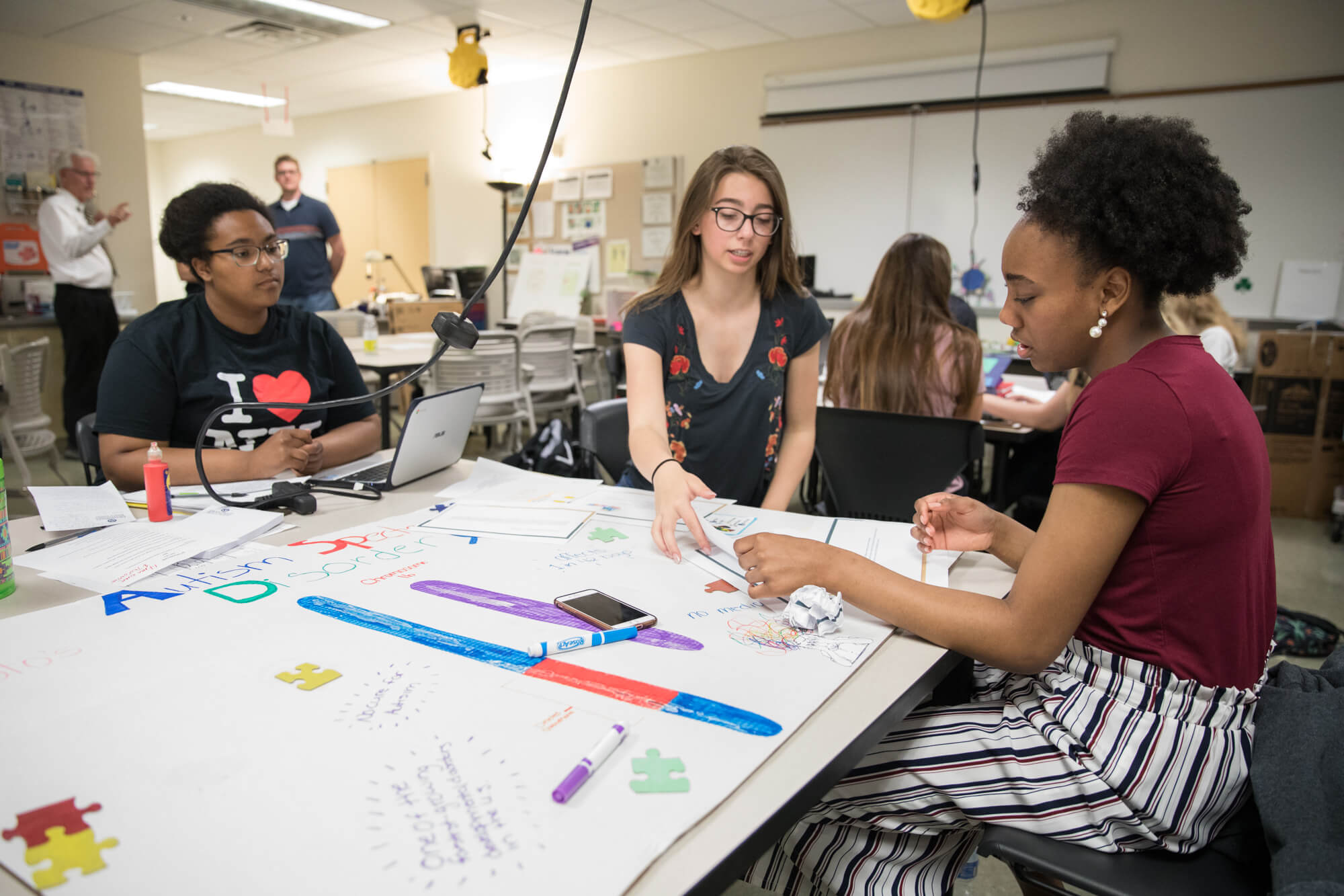 three high school students working on a poster