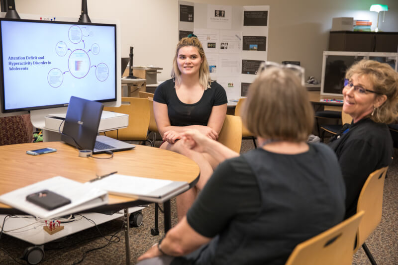 one student discussing presentation in front of two women