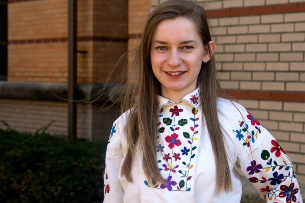 woman standing next to brick wall in colorful, embroidered shirt