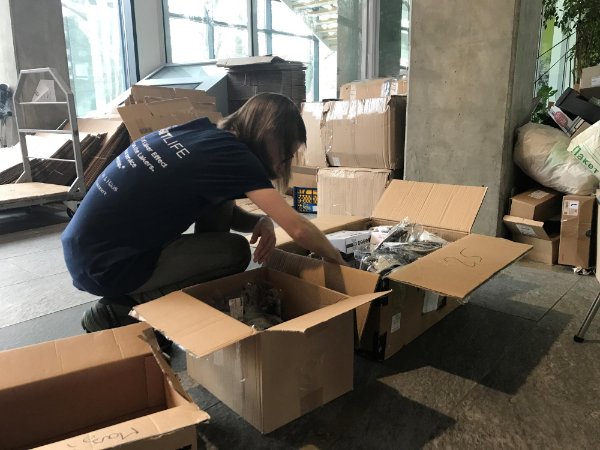 woman hunched over moving boxes, packing them