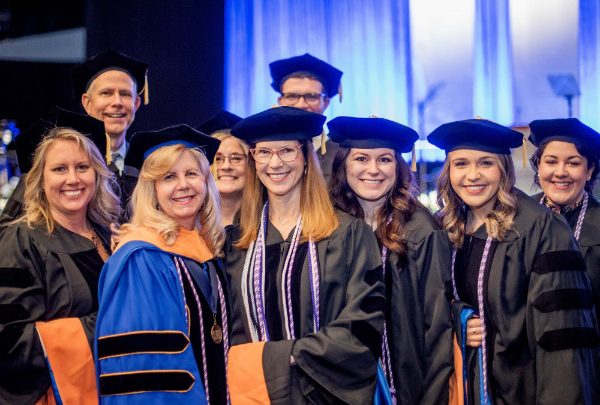 two rows of faculty and students in academic regalia at a commencement ceremony