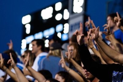 Students at a football game holding their hands up in a Laker L.