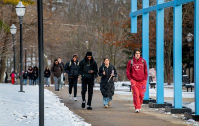 students walking under the blue artwork called the Transformational Link, light snow on the ground