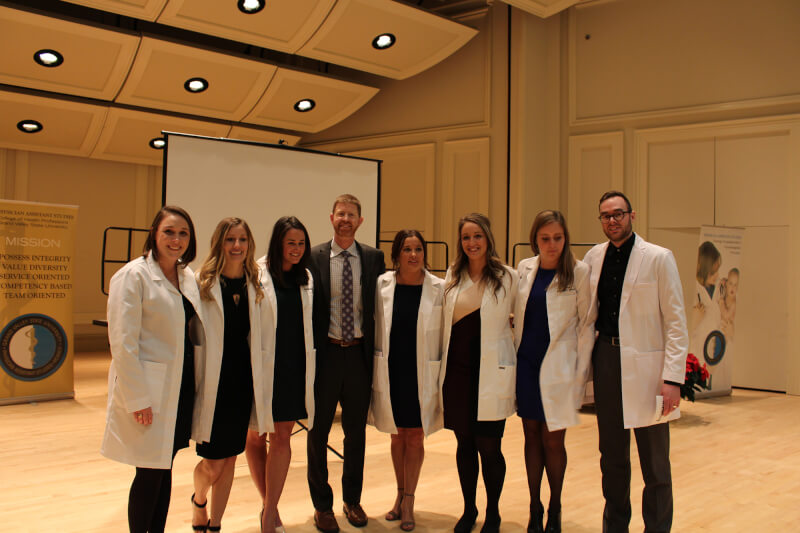 group of students in lab coats with faculty member in center