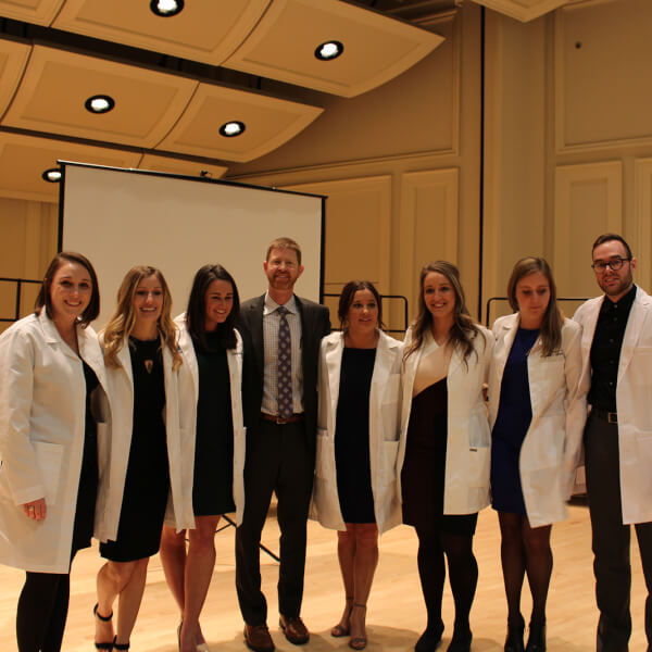 group of students in lab coats with faculty member in center