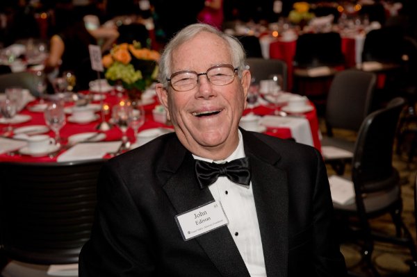 photo of man smiling in tuxedo and black tie, seated at table