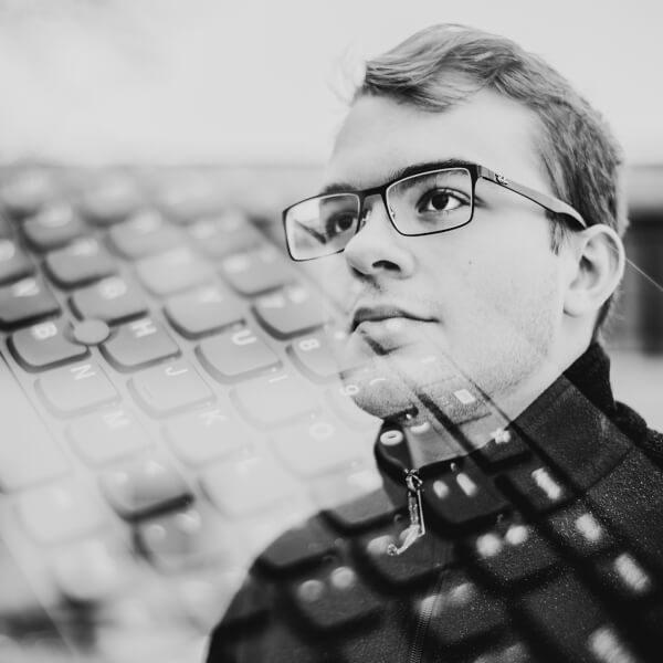 student with glasses, computer keyboard superimposed over his face