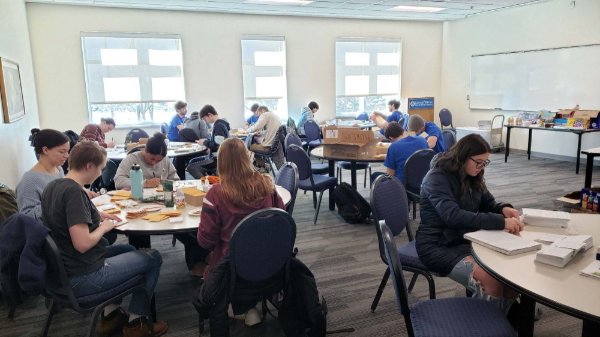 students work at round tables on a volunteer project