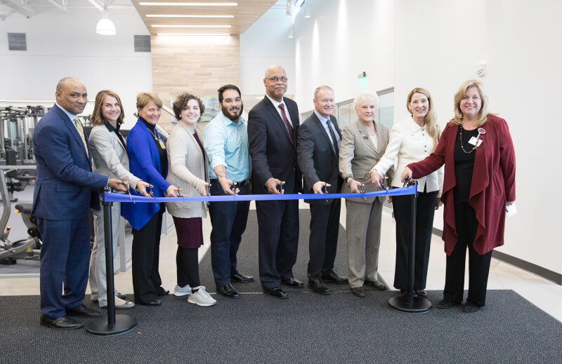 group of people standing with scissors at a ribbon