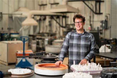 Visual and media arts faculty member Norwood Viviano poses in his studio with some of his 3D-printed art pieces. 