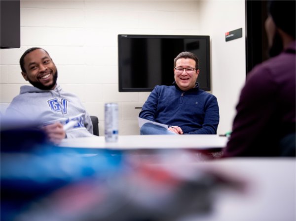 Richard Besel, professor of communications and media studies, center, laughs with students during the first meeting for the speech and debate team January 30.