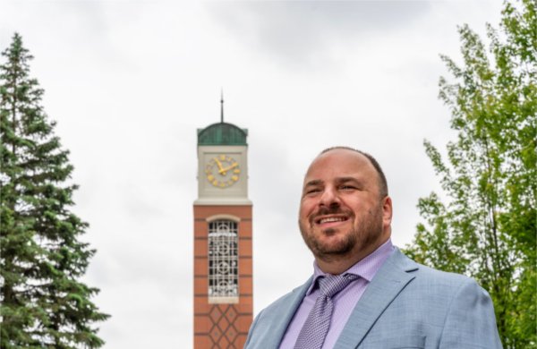 GVSU's new carilloneur poses in front of the Cook Carillon Tower.
