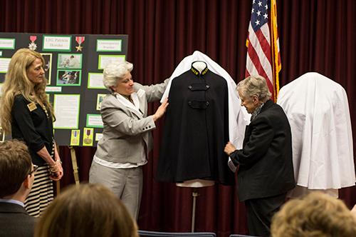 Yvette Petti takes a drape off a World War II nurse's uniform while Martha Pituch, right, and Cynthia McCurren look on.