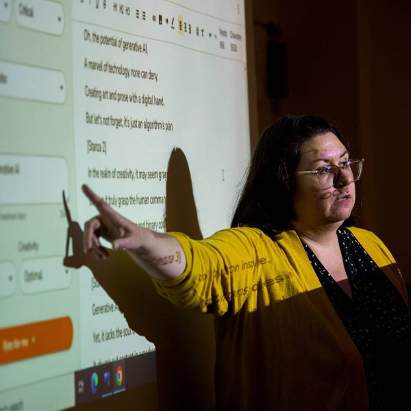 Alisha Karabinus, assistant professor of writing and interdisciplinary studies, points to a projection screen with language generated by AI shown