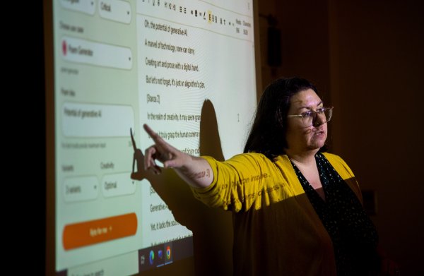 Alisha Karabinus, assistant professor of writing and interdisciplinary studies, points to AI-generated language on a projected screen in her classroom