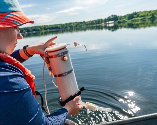 A student researcher uses a water sampler to collect water from McLaren Lake in Oceana County and analyze its salt content. 